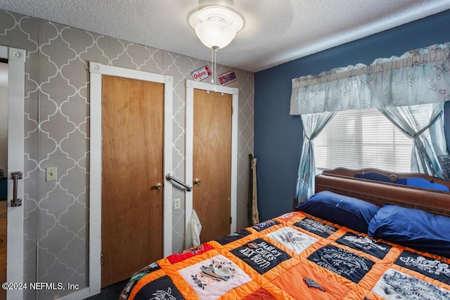 bedroom with wallpapered walls, a closet, and a textured ceiling