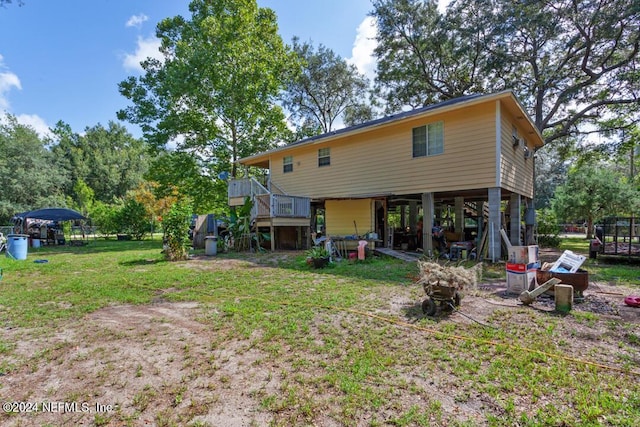 rear view of property with a deck, a carport, stairway, and a lawn