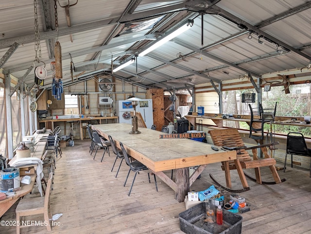 interior space featuring hardwood / wood-style floors, vaulted ceiling, a workshop area, and metal wall