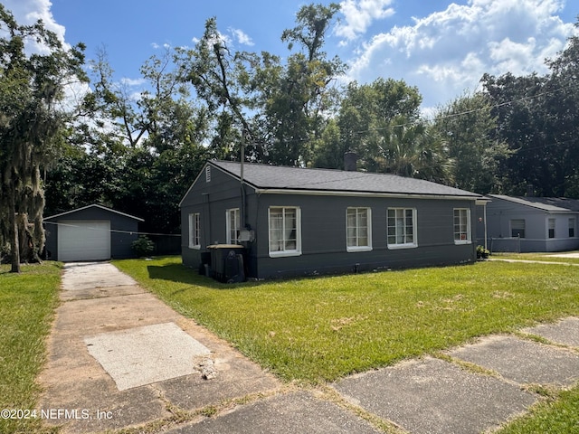 view of front of home featuring a front yard, an outbuilding, and a garage