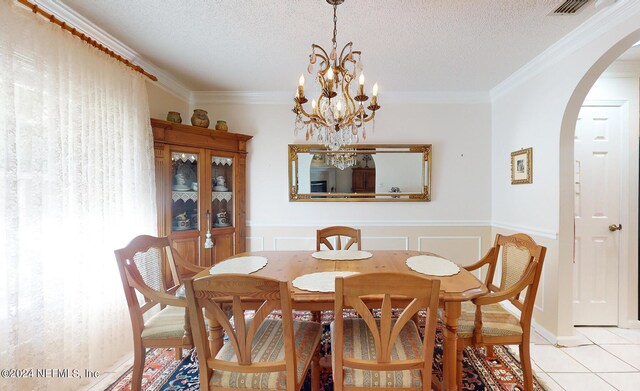 tiled dining area featuring crown molding, a textured ceiling, and a notable chandelier