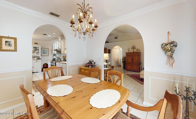 dining area featuring a textured ceiling, crown molding, light tile patterned floors, and a chandelier