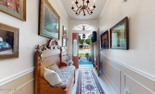 foyer entrance featuring a textured ceiling, a chandelier, crown molding, and tile patterned floors