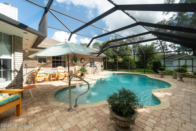 view of pool with glass enclosure and a patio