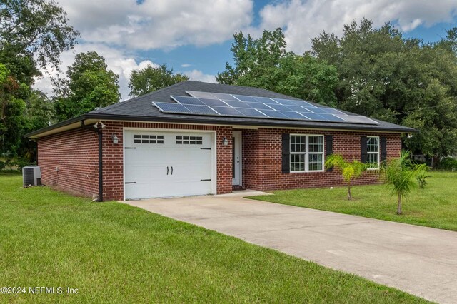 ranch-style home featuring a front lawn, solar panels, a garage, and cooling unit