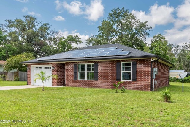 ranch-style house with a front yard, solar panels, and a garage