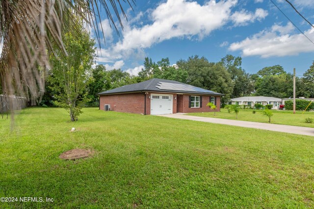 single story home featuring a garage, solar panels, and a front lawn