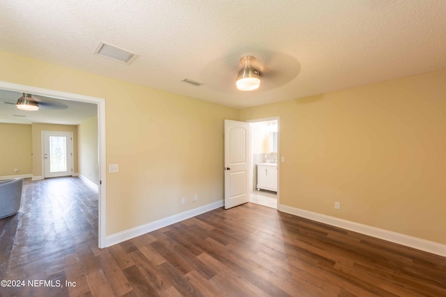 spare room with a textured ceiling, ceiling fan, and dark hardwood / wood-style floors