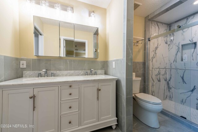 bathroom featuring backsplash, dual vanity, toilet, tile patterned flooring, and tile walls