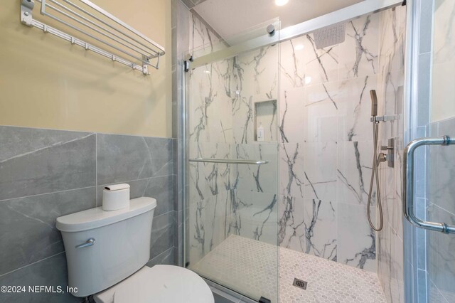 bathroom with tile walls, toilet, and walk in shower