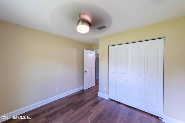 unfurnished bedroom with a closet, ceiling fan, and dark hardwood / wood-style floors