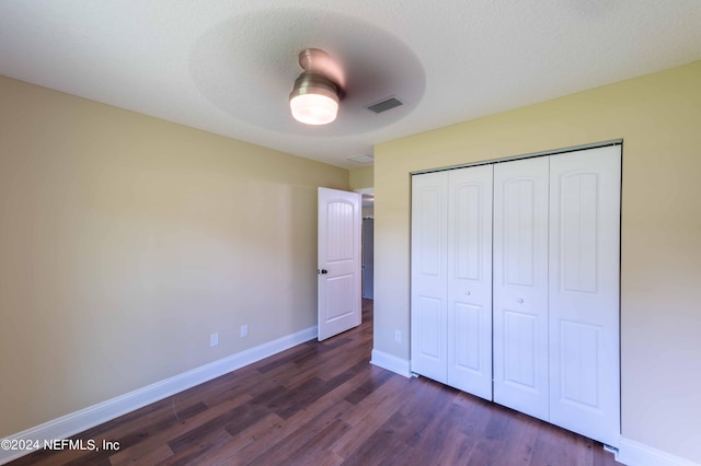 unfurnished bedroom featuring a textured ceiling, a closet, ceiling fan, and dark hardwood / wood-style floors