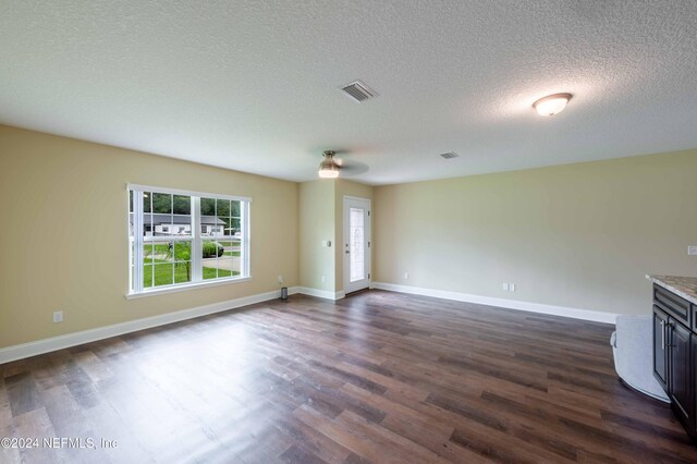 unfurnished living room featuring dark wood-type flooring and a textured ceiling