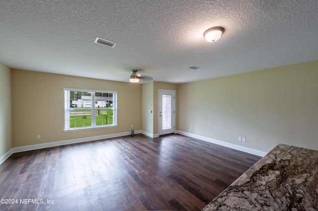 unfurnished room with a textured ceiling and dark wood-type flooring