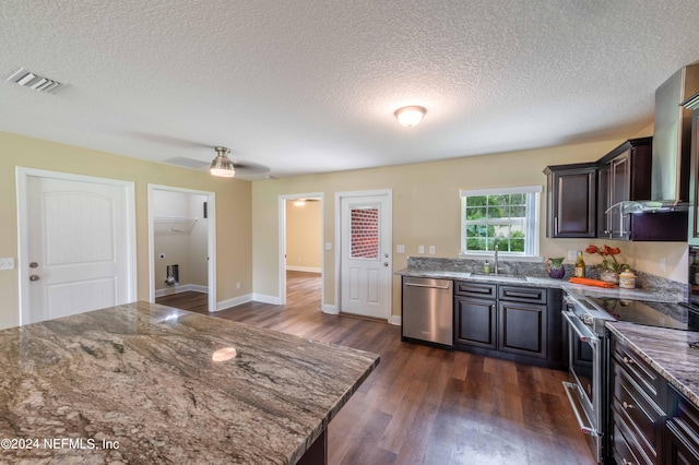 kitchen with dark hardwood / wood-style floors, stainless steel appliances, wall chimney exhaust hood, and light stone countertops