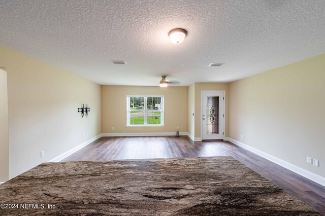 empty room featuring a textured ceiling and dark hardwood / wood-style floors