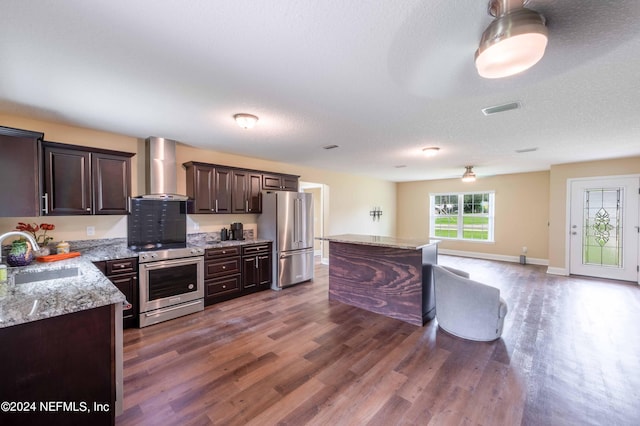 kitchen featuring dark hardwood / wood-style floors, wall chimney exhaust hood, sink, a center island, and stainless steel appliances