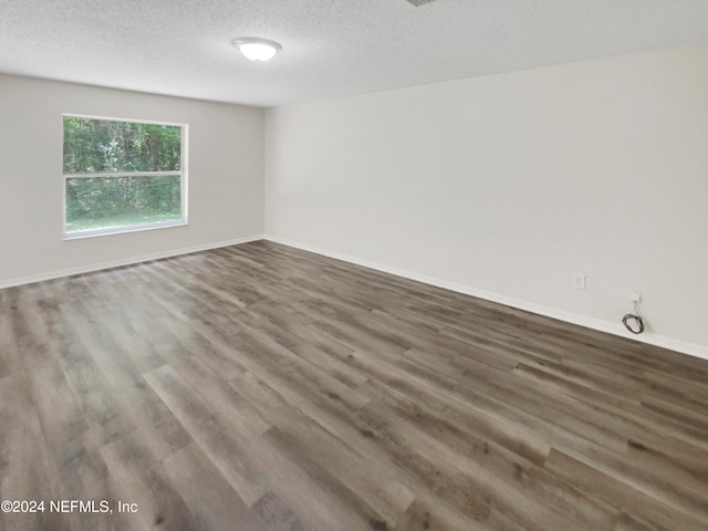 empty room with hardwood / wood-style flooring and a textured ceiling