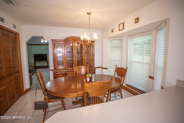 dining room with a textured ceiling, a notable chandelier, and light tile patterned flooring