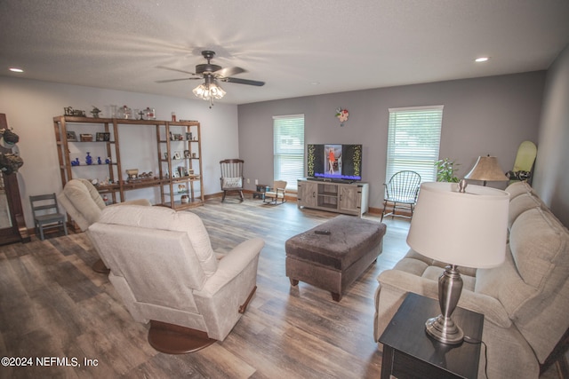 living room featuring ceiling fan, a textured ceiling, and wood-type flooring