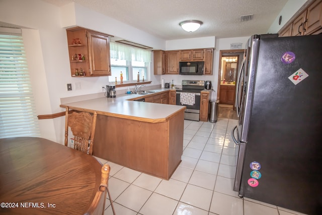 kitchen featuring kitchen peninsula, light tile patterned flooring, and black appliances