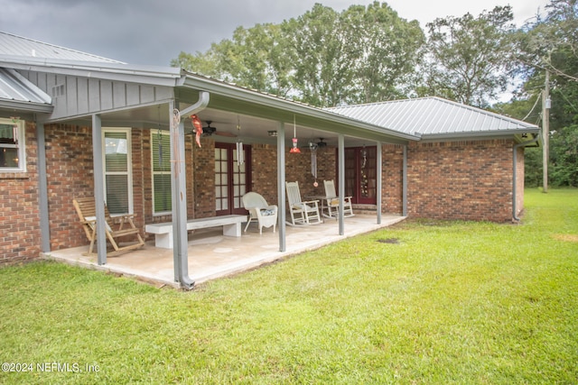 back of property featuring ceiling fan, a patio, and a lawn