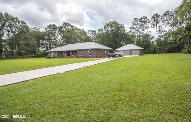 ranch-style home featuring a front lawn, a garage, and an outbuilding