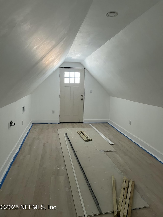 bonus room with vaulted ceiling, light wood-style flooring, and baseboards