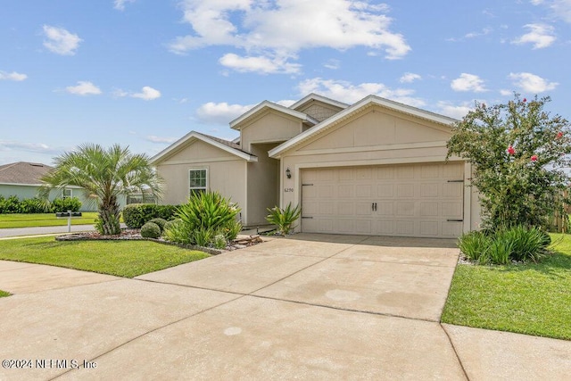 view of front of property with a front yard, concrete driveway, an attached garage, and stucco siding