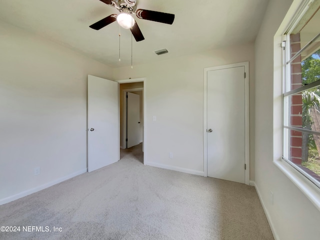 unfurnished bedroom featuring ceiling fan, light carpet, and multiple windows