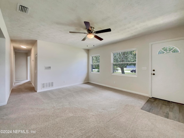 carpeted foyer entrance featuring a textured ceiling and ceiling fan