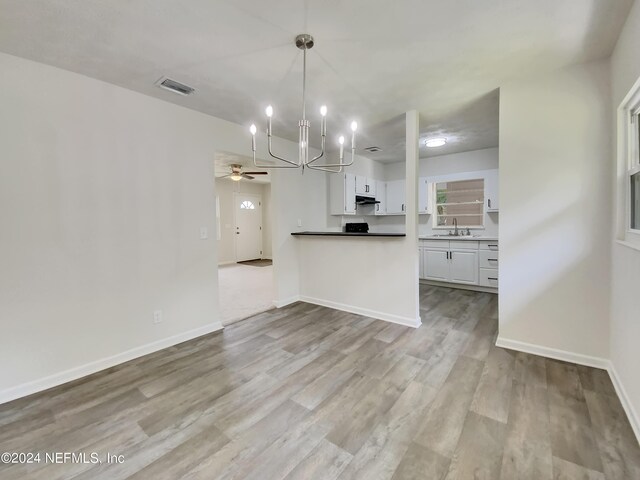 kitchen with pendant lighting, ceiling fan with notable chandelier, white cabinetry, light hardwood / wood-style floors, and kitchen peninsula