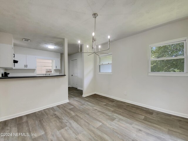 interior space with white cabinets, hanging light fixtures, light hardwood / wood-style flooring, and a chandelier