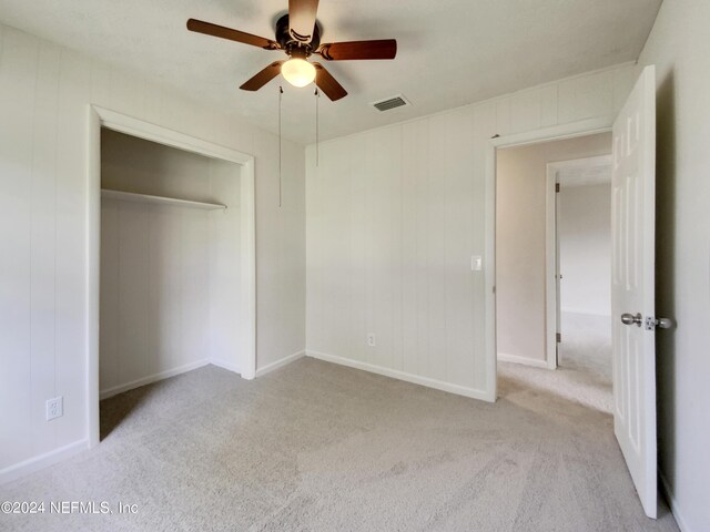 unfurnished bedroom with ceiling fan, light carpet, and a closet