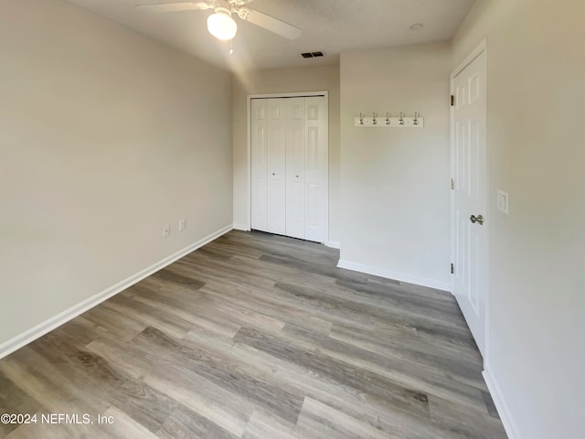 unfurnished bedroom featuring ceiling fan, hardwood / wood-style flooring, and a closet