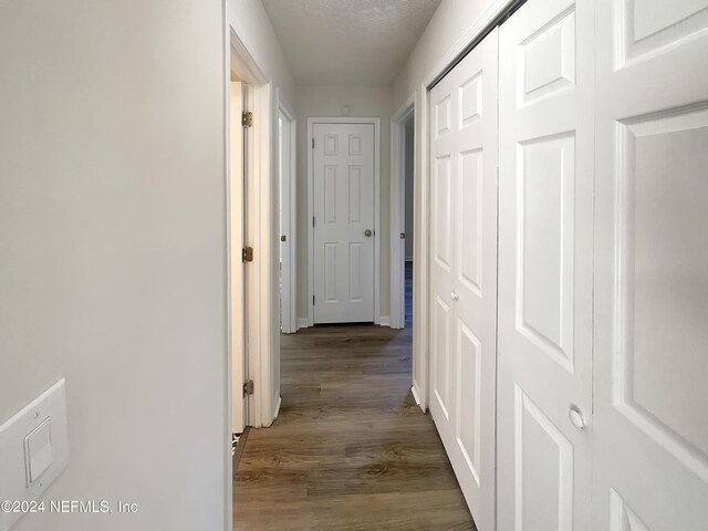 corridor with a textured ceiling and hardwood / wood-style flooring