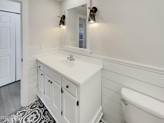 bathroom with toilet, hardwood / wood-style flooring, vanity, and tile walls