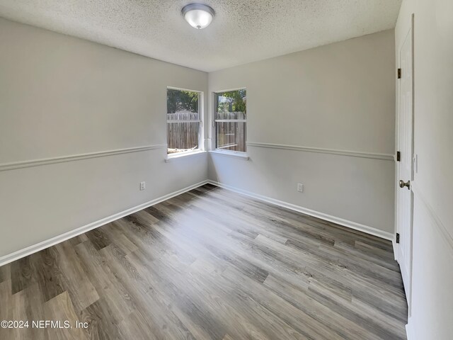 empty room featuring a textured ceiling and wood-type flooring