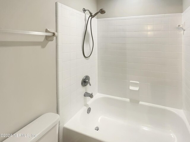 bathroom with tiled shower / bath combo and toilet