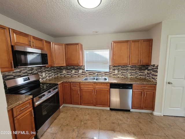 kitchen featuring appliances with stainless steel finishes, backsplash, sink, a textured ceiling, and light tile patterned floors