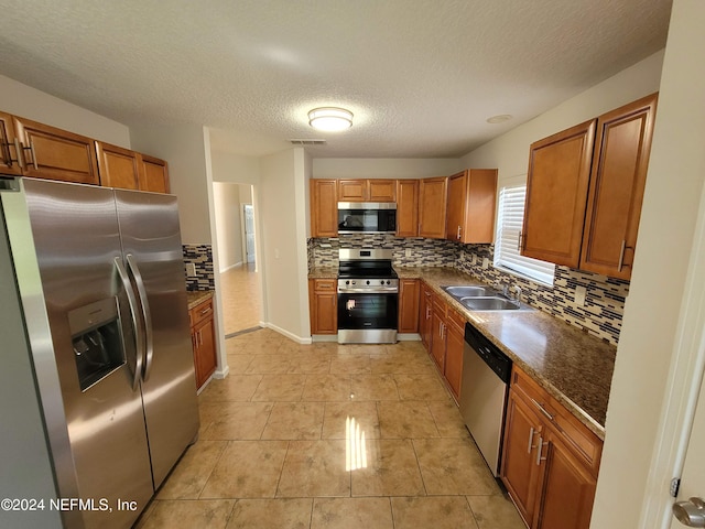 kitchen featuring decorative backsplash, light tile patterned floors, sink, a textured ceiling, and stainless steel appliances