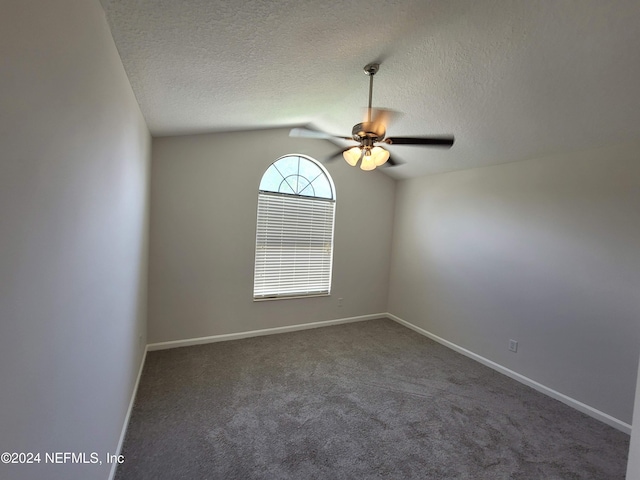 empty room featuring ceiling fan, vaulted ceiling, a textured ceiling, and carpet