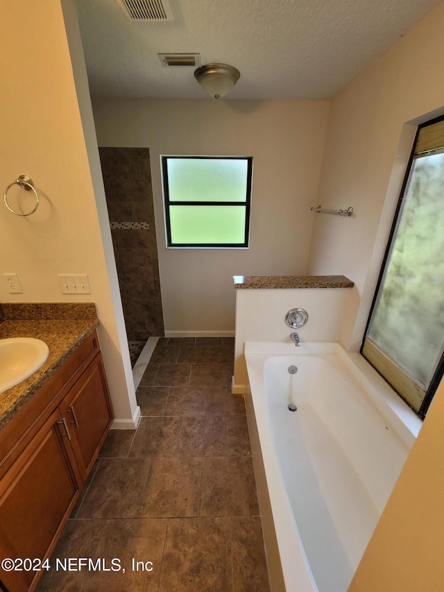 bathroom featuring shower with separate bathtub, tile patterned flooring, a textured ceiling, and vanity