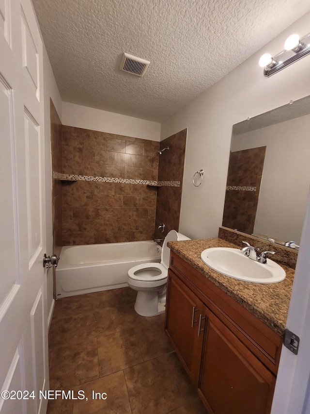 full bathroom with vanity, tile patterned floors, a textured ceiling, toilet, and tiled shower / bath combo