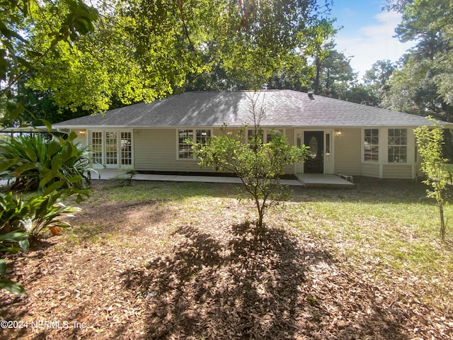 view of front of home with a patio area, french doors, a front yard, and a shingled roof