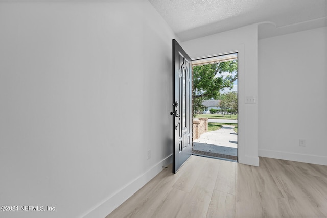 entrance foyer with light wood-type flooring and a textured ceiling