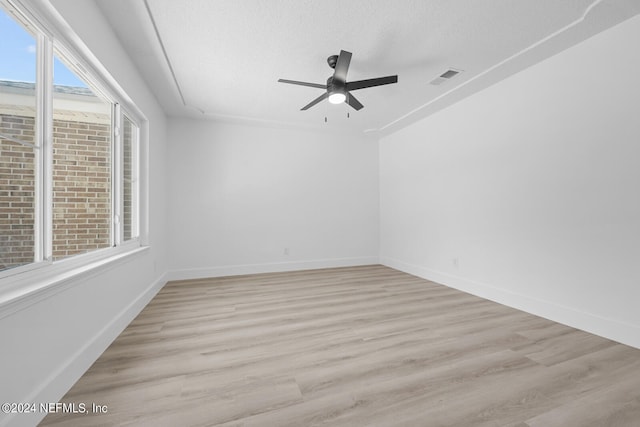 spare room with light hardwood / wood-style floors, ceiling fan, and a textured ceiling