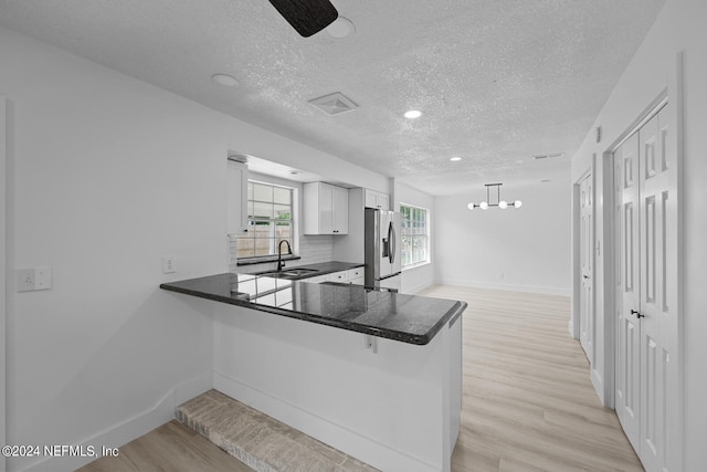 kitchen featuring white cabinetry, kitchen peninsula, light wood-type flooring, and stainless steel fridge with ice dispenser