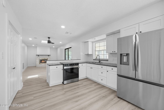 kitchen featuring stainless steel appliances, sink, kitchen peninsula, light hardwood / wood-style flooring, and white cabinets