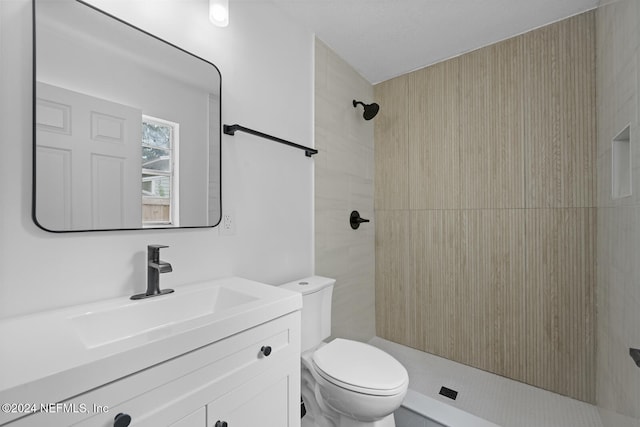 bathroom featuring toilet, vanity, and tiled shower